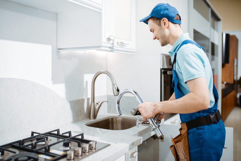 plumber-in-uniform-changes-faucet-in-the-kitchen.jpg